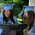 Two students in Carolina blue commencement robes near the Old Well
