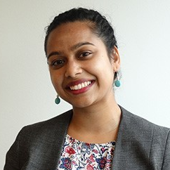 Judy Prasad headshot wearing a suit and green earrings